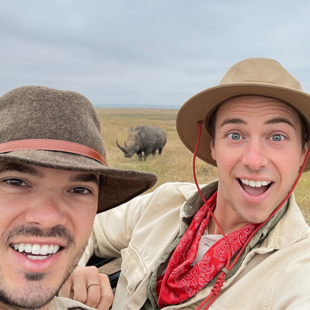 two men ethically posing with a white rhino on safari