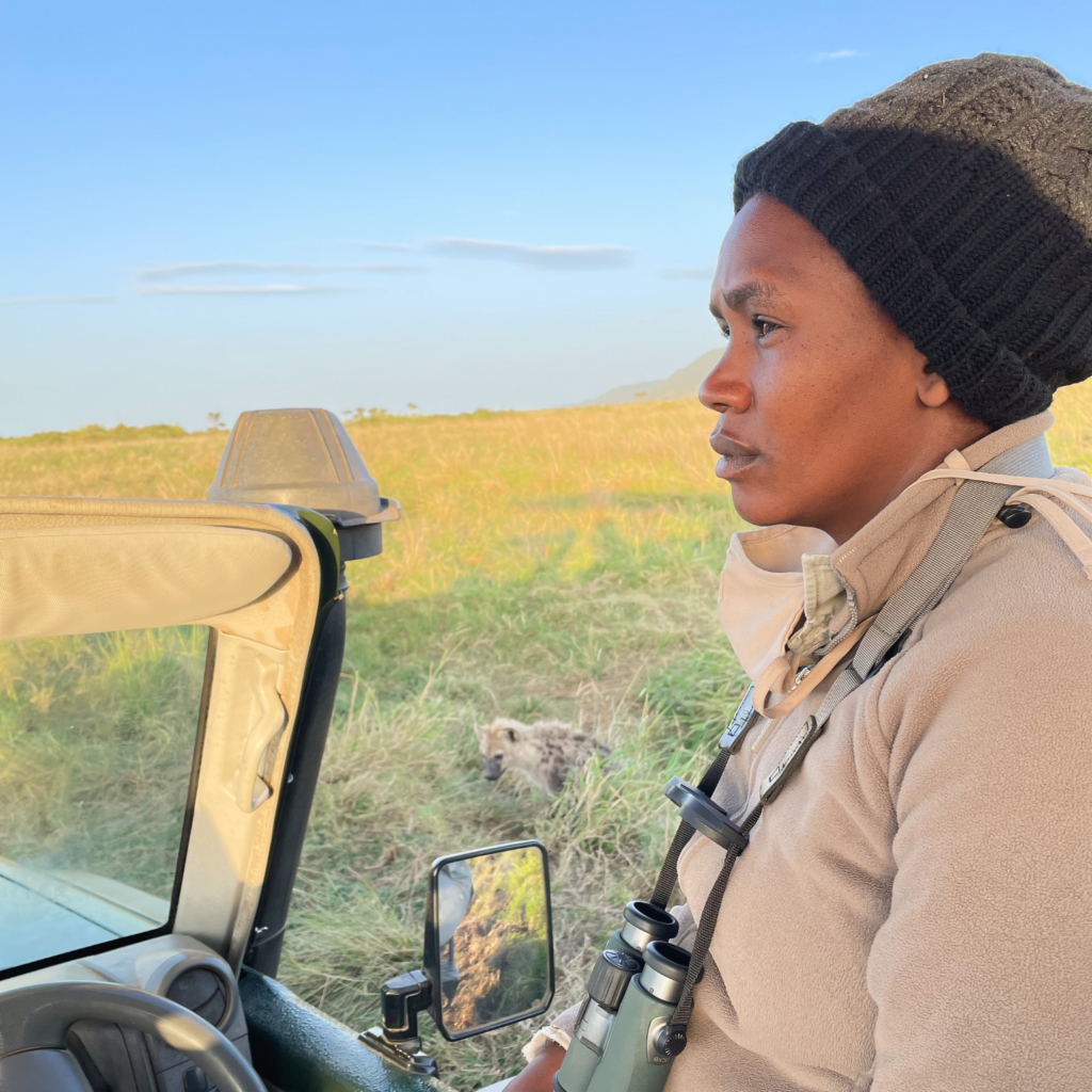 Female safari guide with a hyena pup close by in Kenya