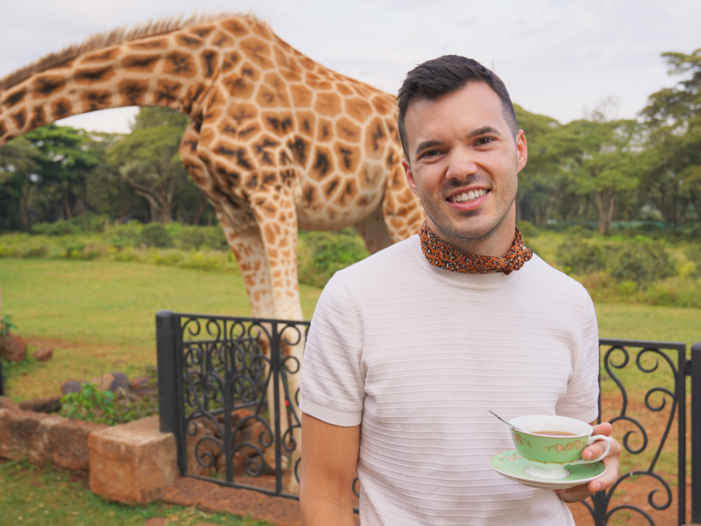 young man enjoying afternoon tea with the giraffes at Giraffe Manor