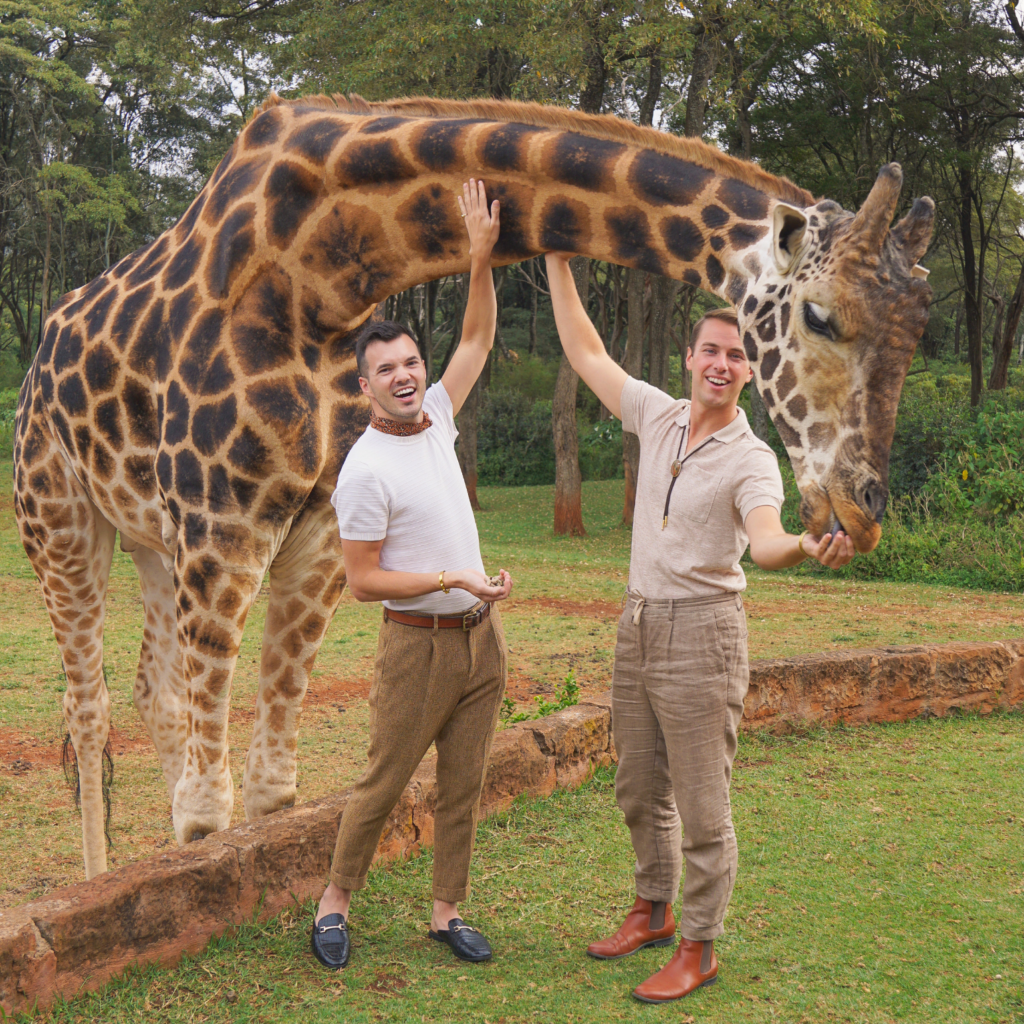 a gay couple feeding a giraffe at Giraffe manor in Nairobi, Kenya