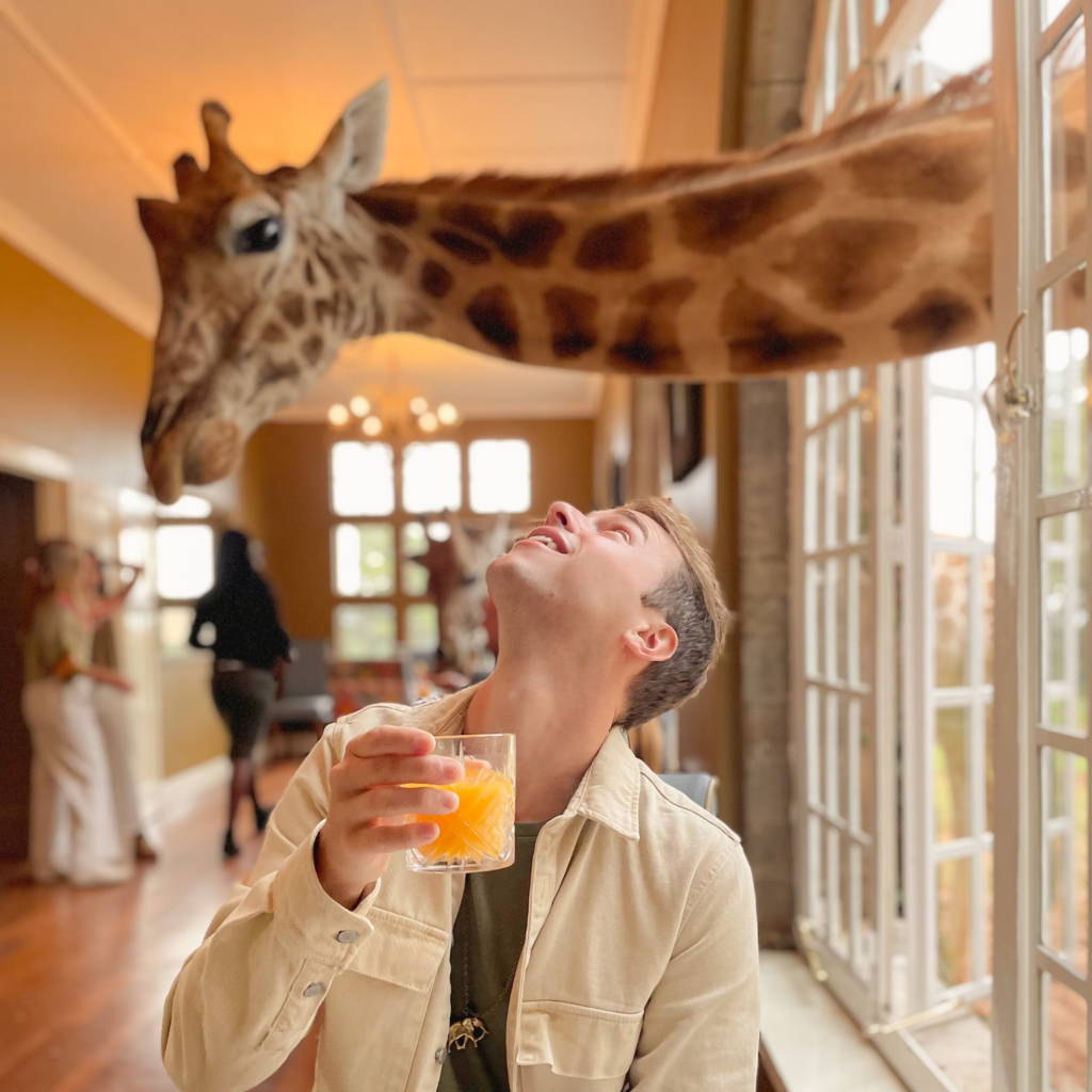 young man enjoying breakfast with the giraffes at Giraffe Manor