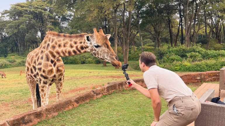 young man filming a giraffe at Giraffe Manor