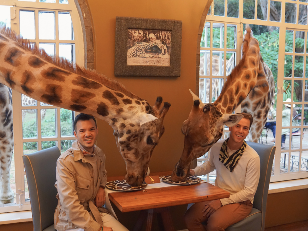 a gay couple feeding giraffes during breakfast at Giraffe manor in Nairobi, Kenya